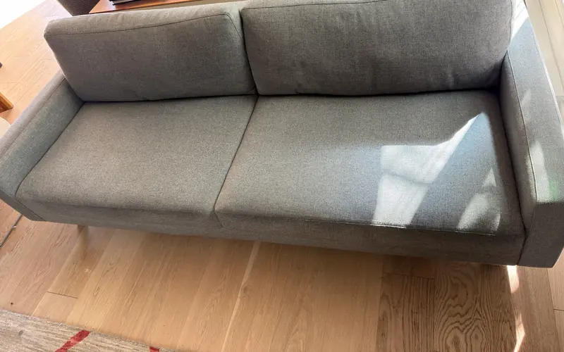 Gray woven sofa after cleaning, in morning sun.